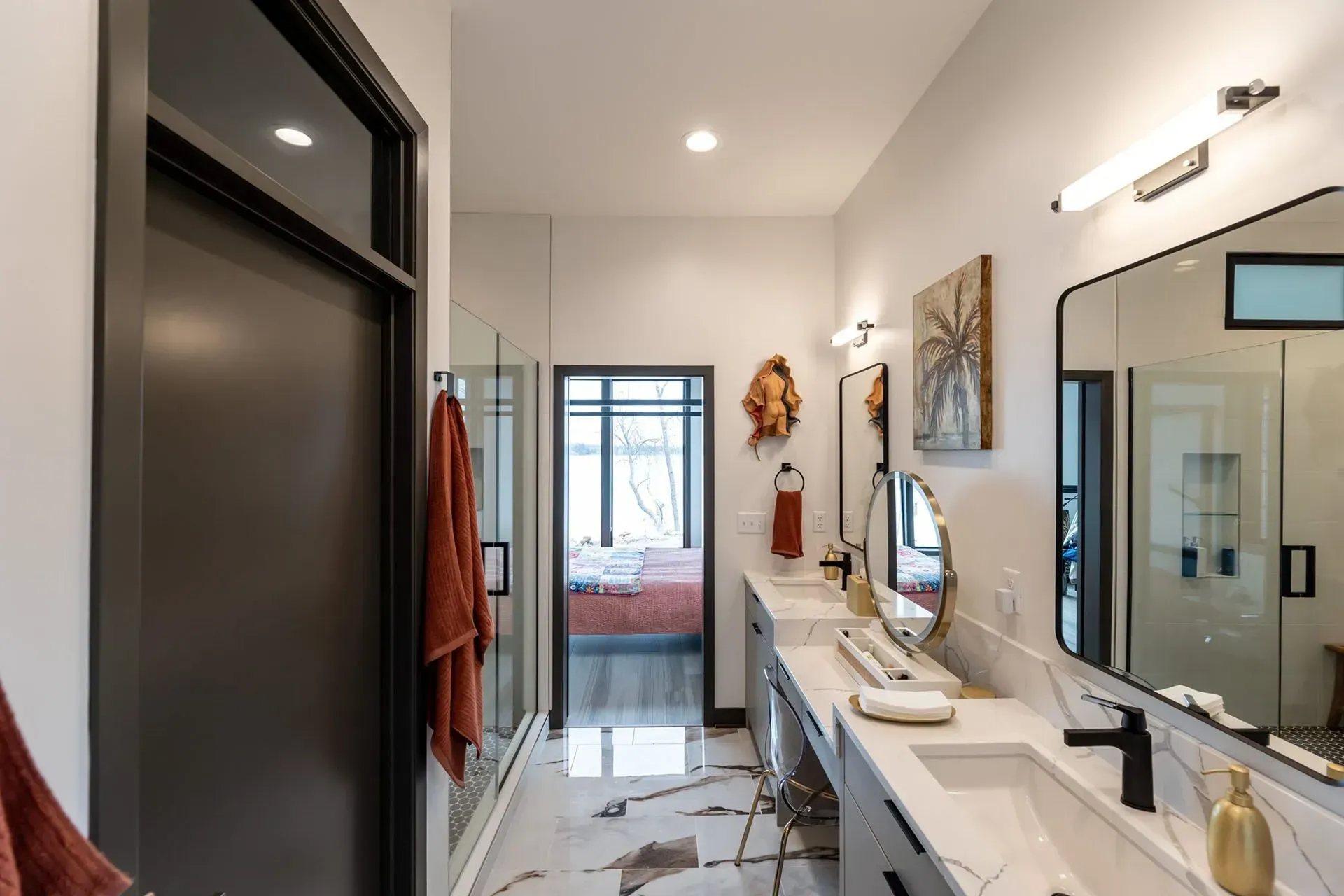 Modern bathroom with marble floors, double sinks, and a view into a bedroom.