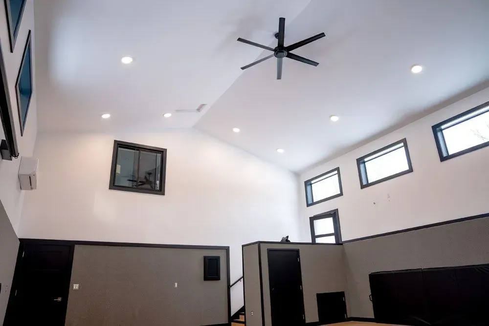 High-ceilinged room with white walls, black trim, recessed lights, and a black ceiling fan.