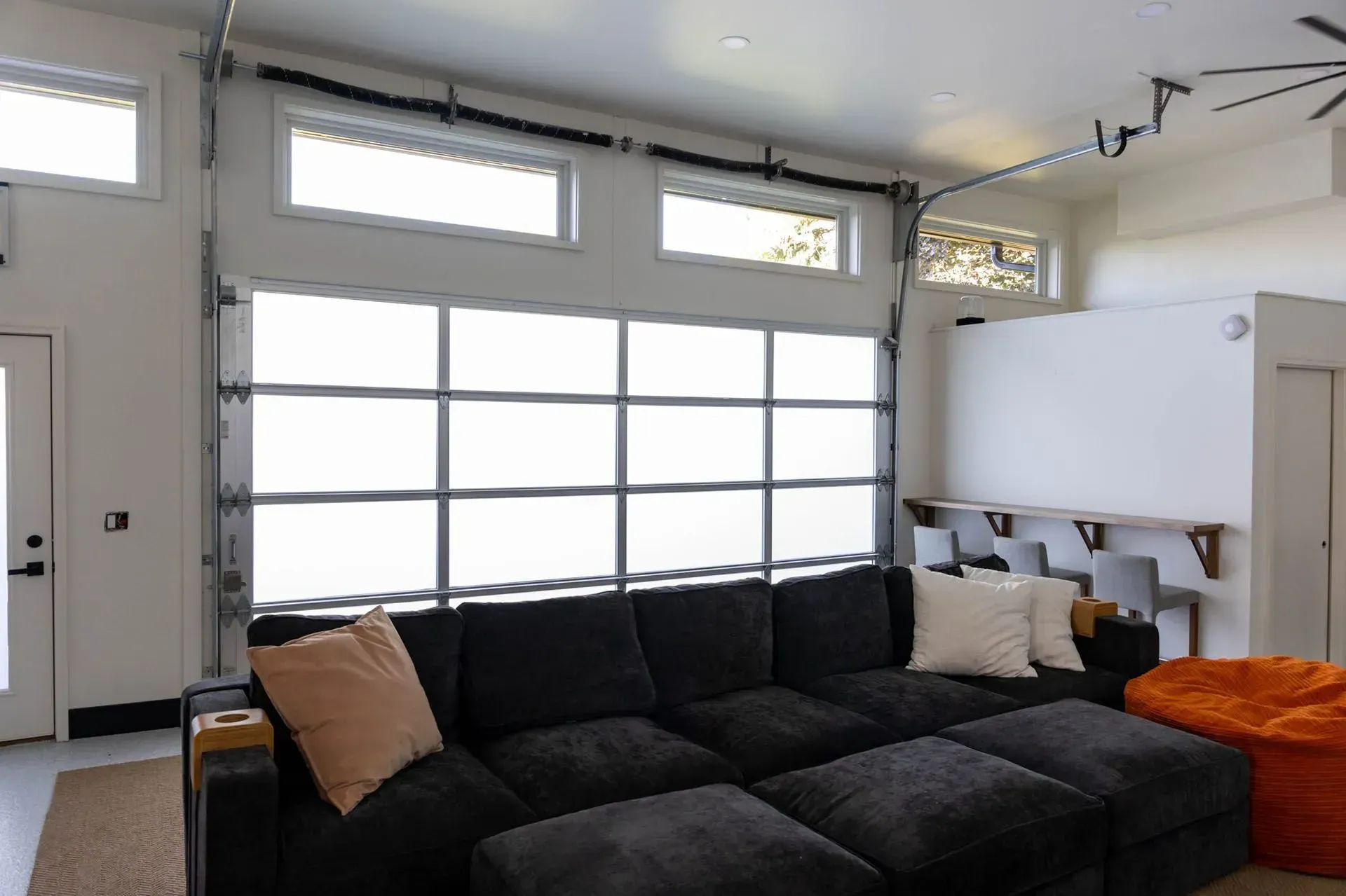 Living room with dark gray sectional sofa in front of a frosted glass garage door.