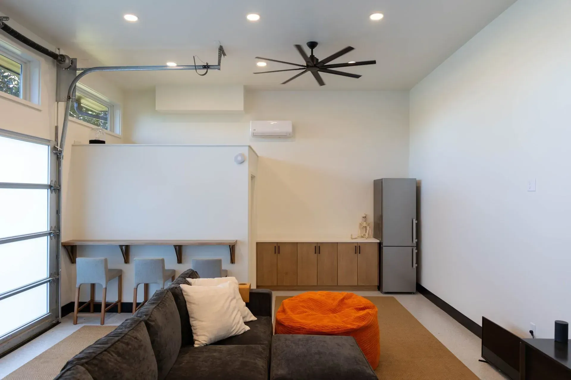Modern living room with sectional sofa, bar, and refrigerator.
