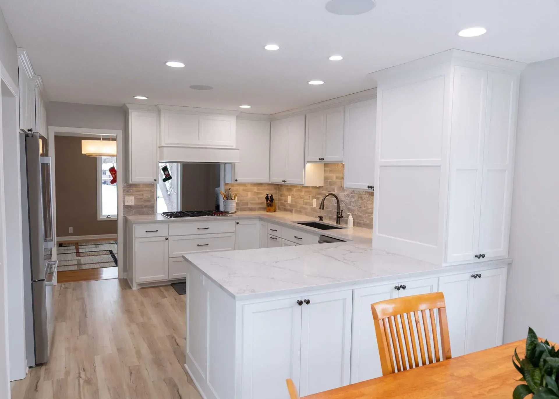 White kitchen with island, cabinets, appliances, and wood flooring.