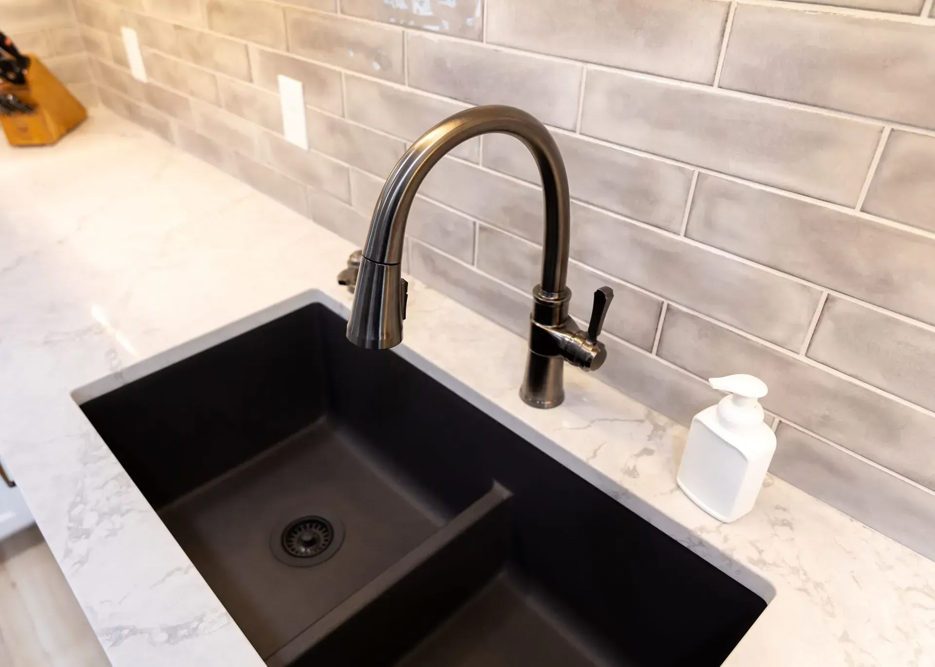 Black double kitchen sink with a dark faucet and a white soap dispenser.