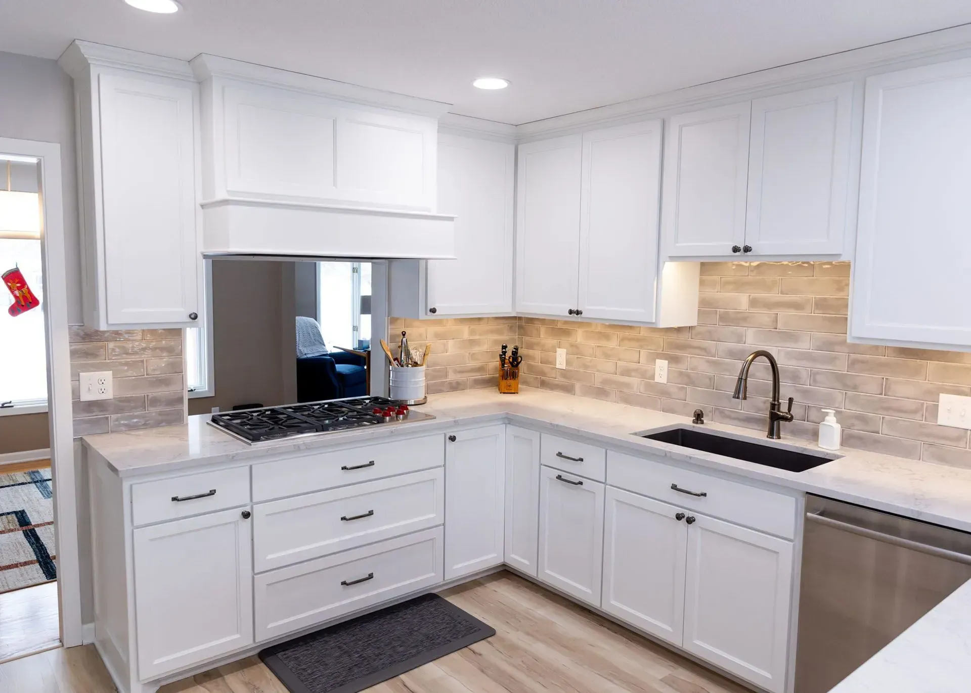 White kitchen with cabinets, stove, sink, and tiled backsplash.