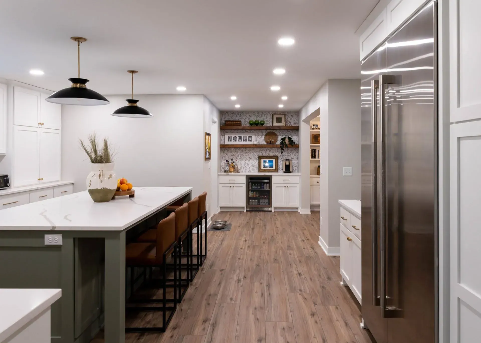 Modern kitchen with green island, white cabinets, stainless steel fridge, and wood floors.