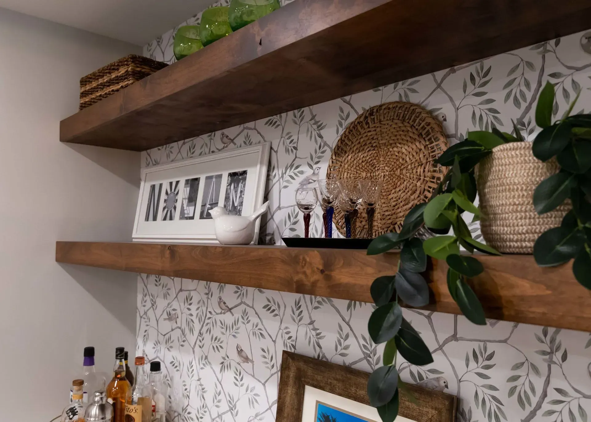 Wooden shelves with decor against floral wallpaper.