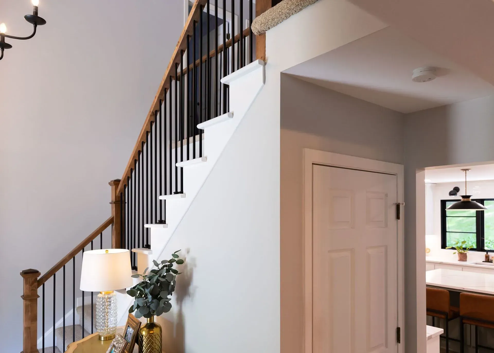 A staircase with wooden steps and black railing. A white door is on the right.