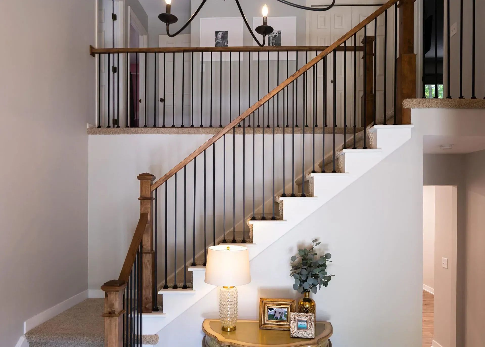 Staircase with white steps, dark metal railings, and wood accents, leading to an upper level.