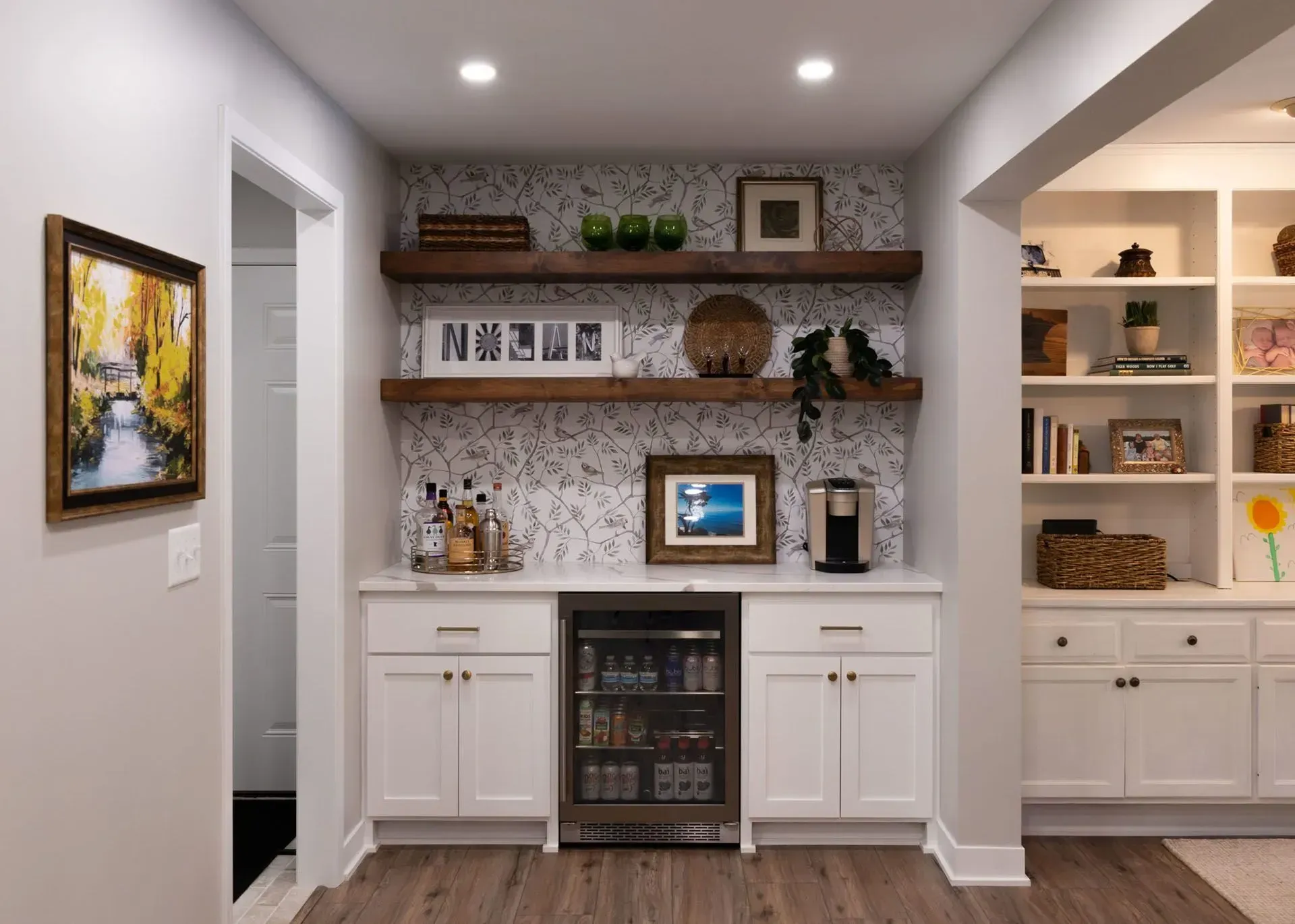 Basement bar with white cabinets, wood shelves, and a patterned backsplash.
