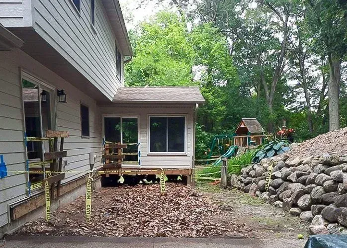Backyard house view with a small deck under construction, and a play structure visible.