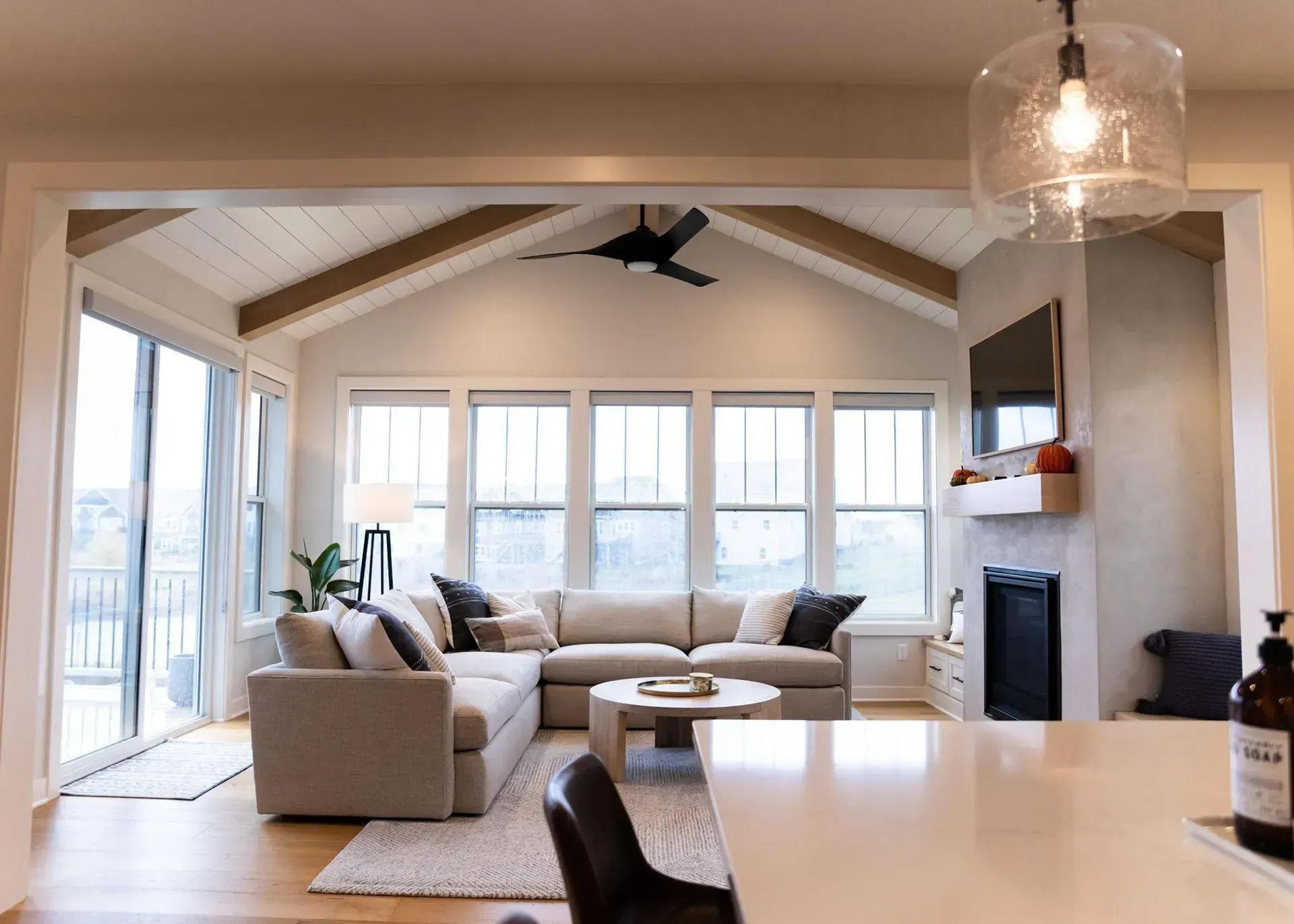 Cozy living room with light-colored sectional sofa, fireplace, and large windows.