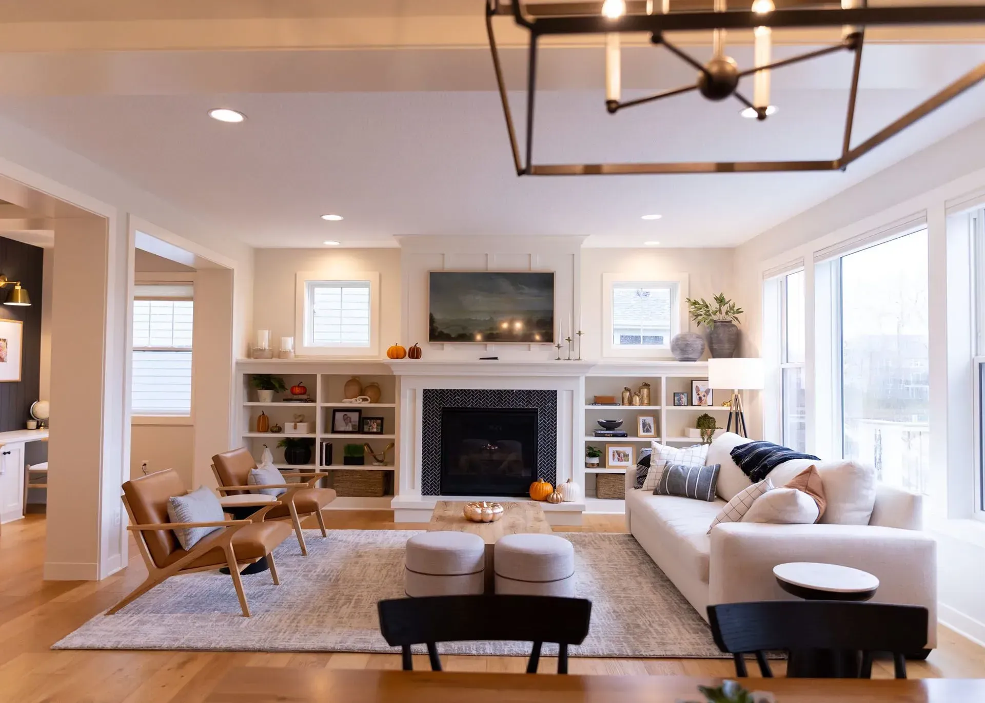 Living room with fireplace, built-in shelves, white sofa, wooden chairs, and a neutral color palette.