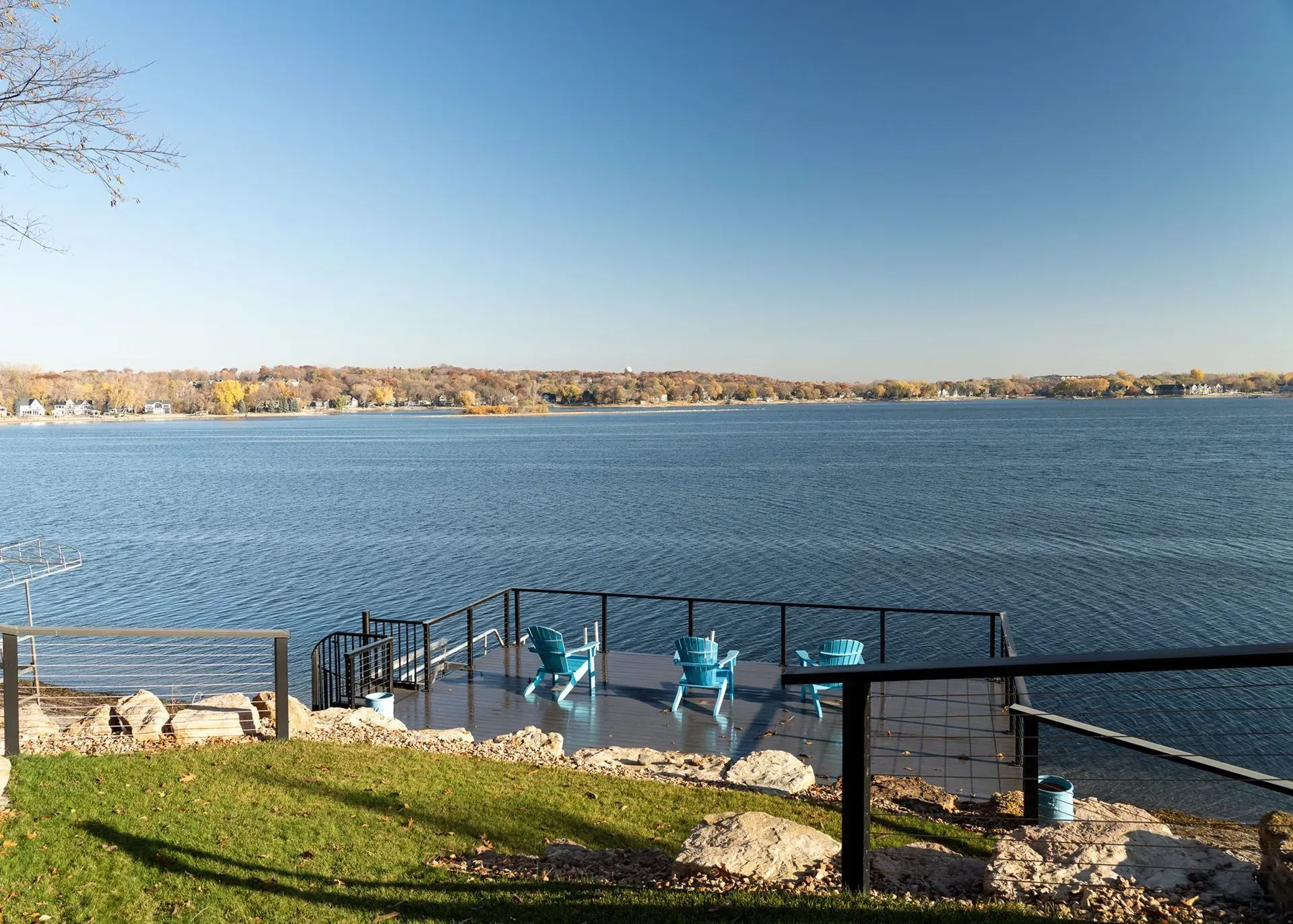 Lake view with blue chairs on a platform, sunny day.