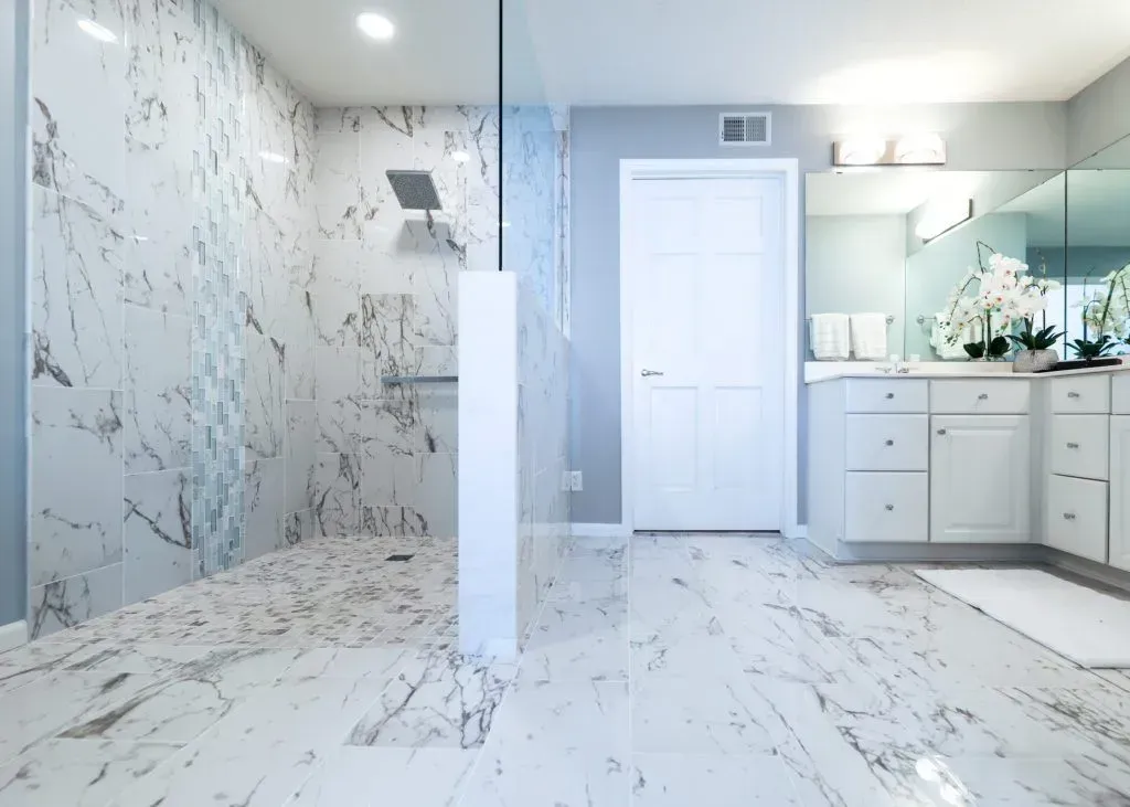 Luxurious marble bathroom with large shower, white vanity, and mirrored wall.