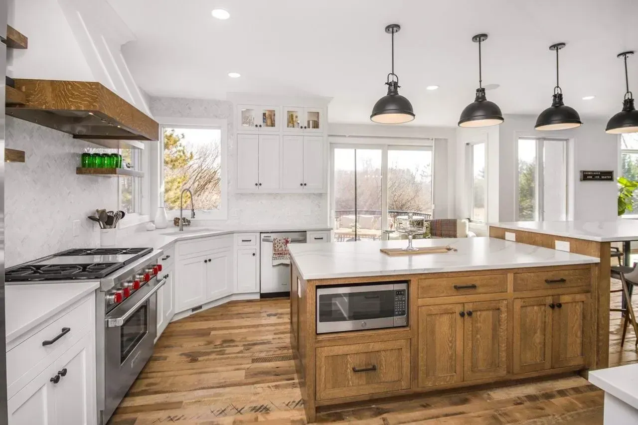 Modern kitchen with white cabinets, wood island, stainless steel appliances, and large windows.