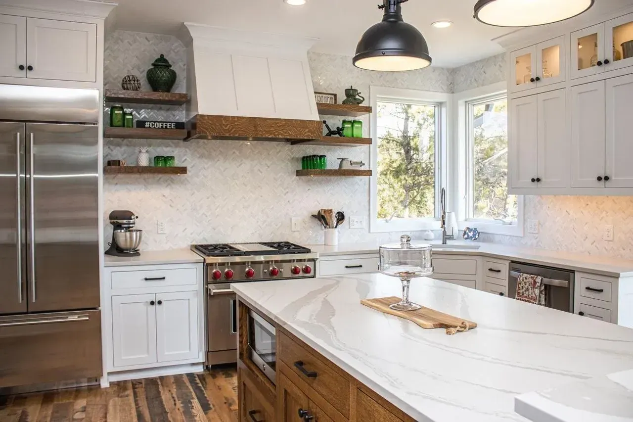 Modern kitchen with white cabinets, stainless steel appliances, and a marble countertop island.