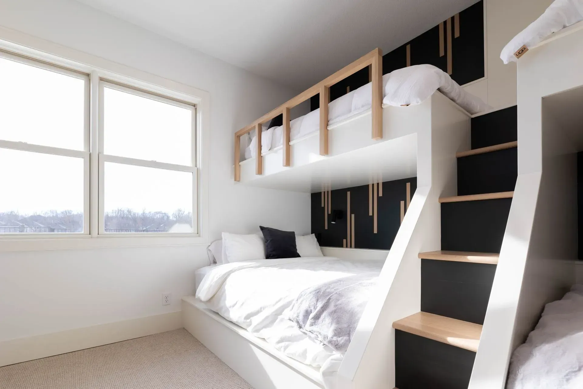 Bunk bed in a white room with black accents, natural wood trim, and a window.