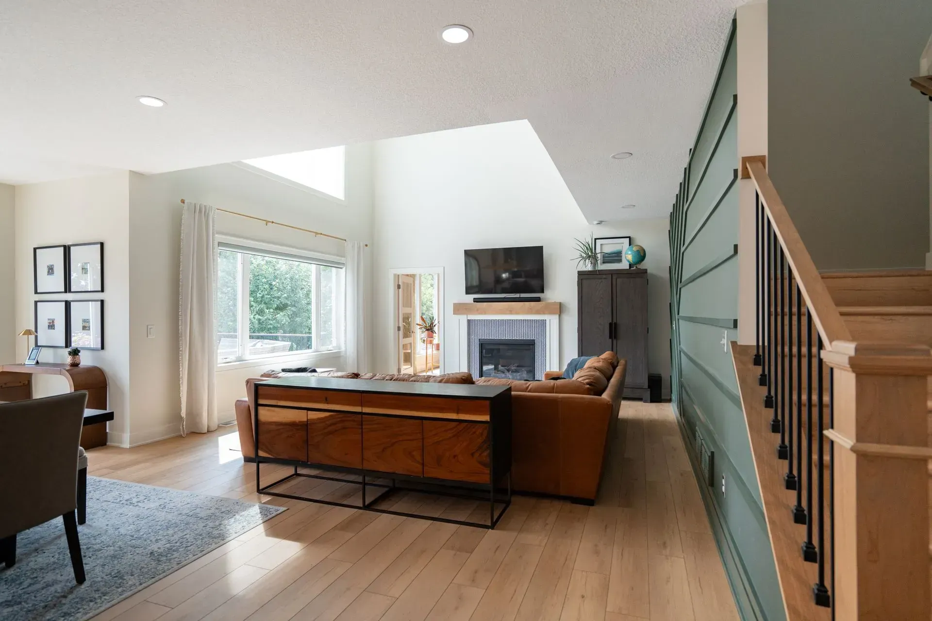 Living room with brown leather sofa, fireplace, and staircase.