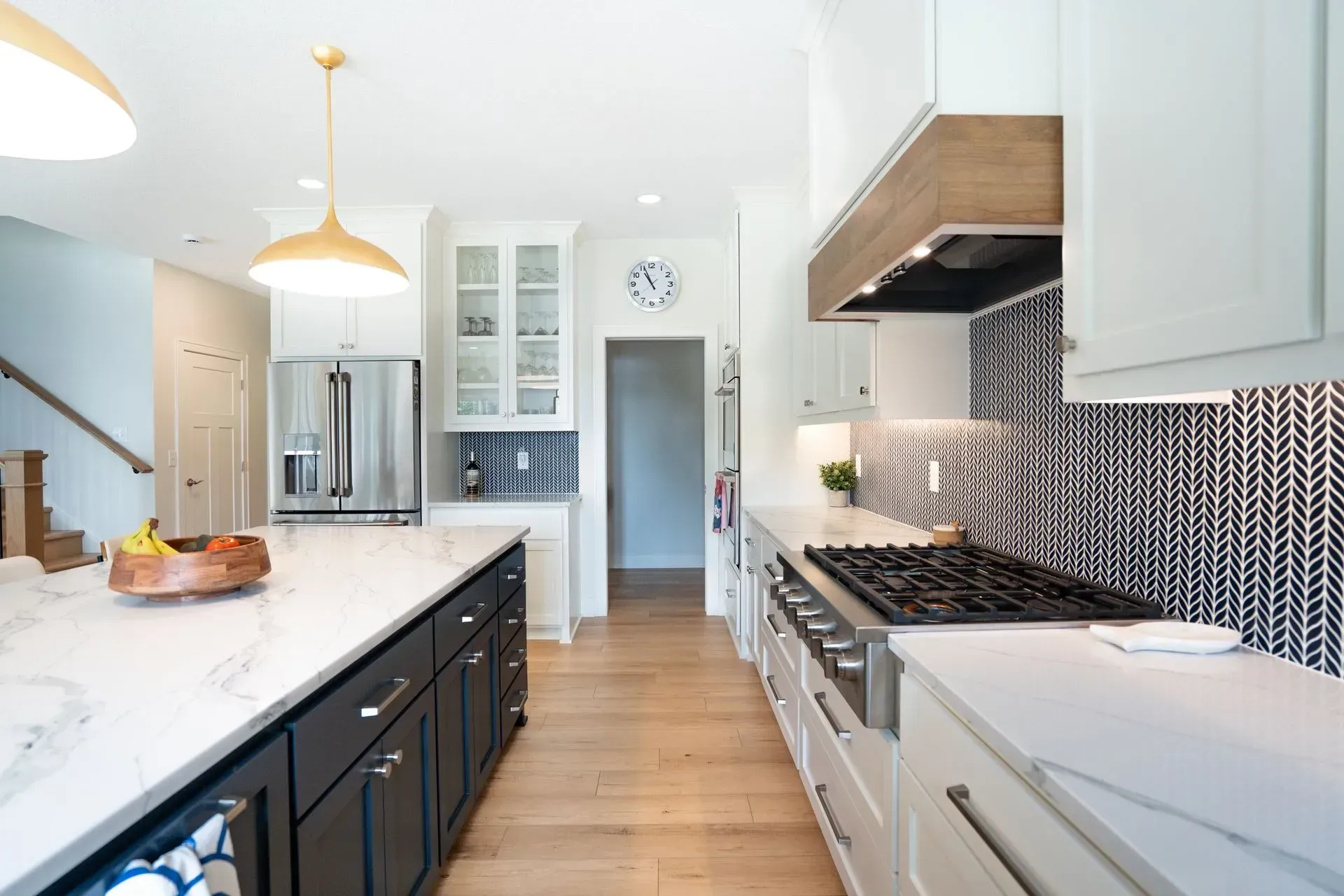 Modern kitchen with island, countertops, stainless steel appliances, and wood flooring.
