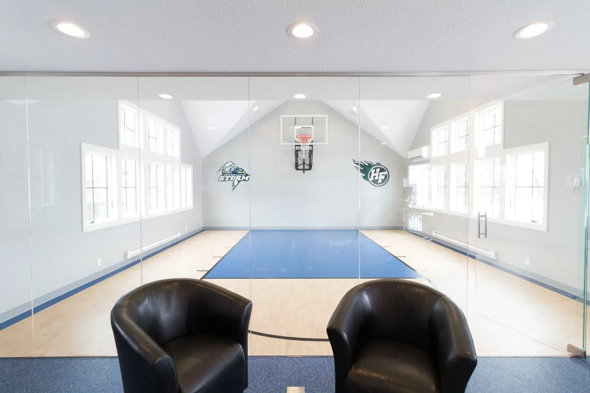 A home basketball court with two black armchairs in front of a glass wall.