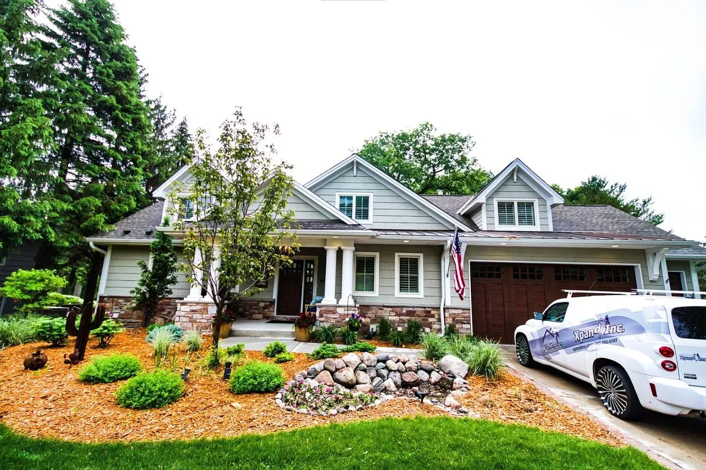 Curb appeal of a house with stone accents, a landscaped yard, and a white van parked in the driveway.