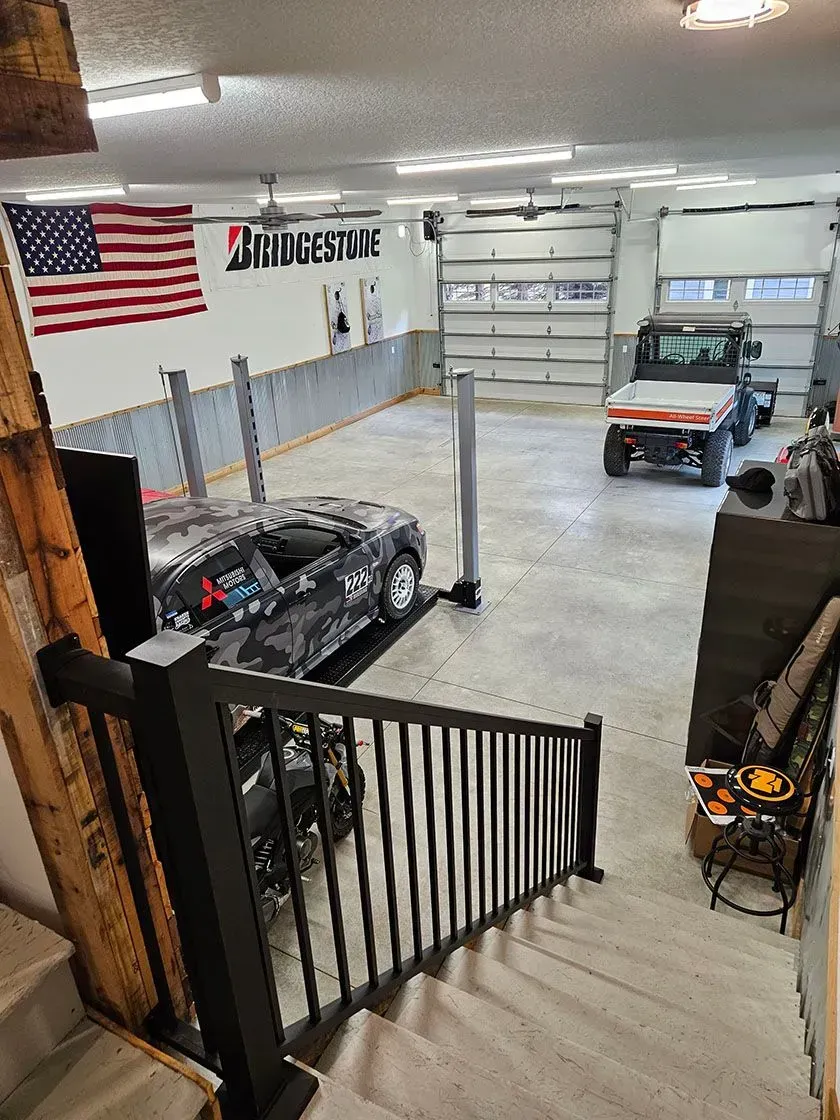 Garage with a car on a lift, a truck, an American flag, and Bridgestone sign.