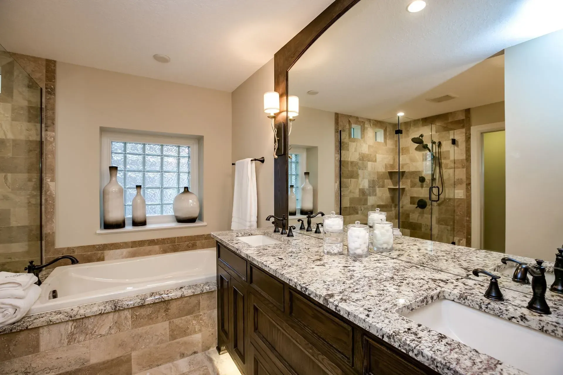 Bathroom with granite countertop vanity, tub, and glass block window.