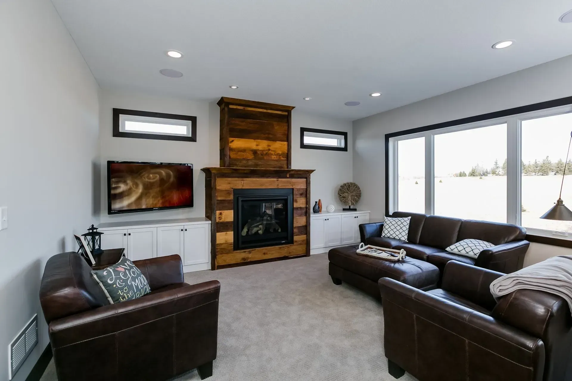Living room with leather furniture, fireplace, and large windows.