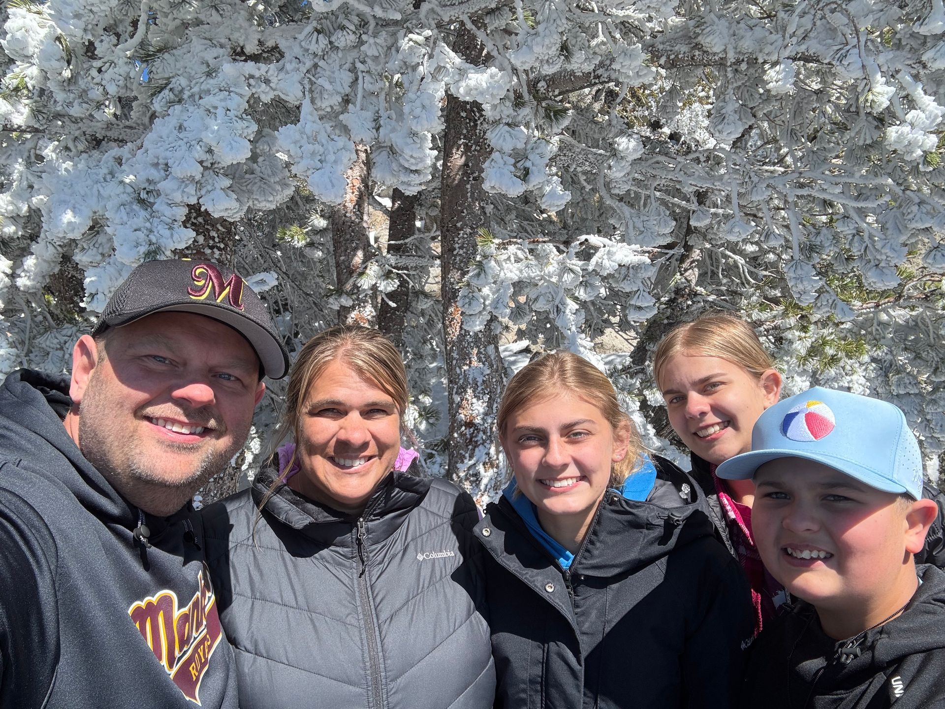Five people smiling for a selfie in front of a rocky cliff outdoors