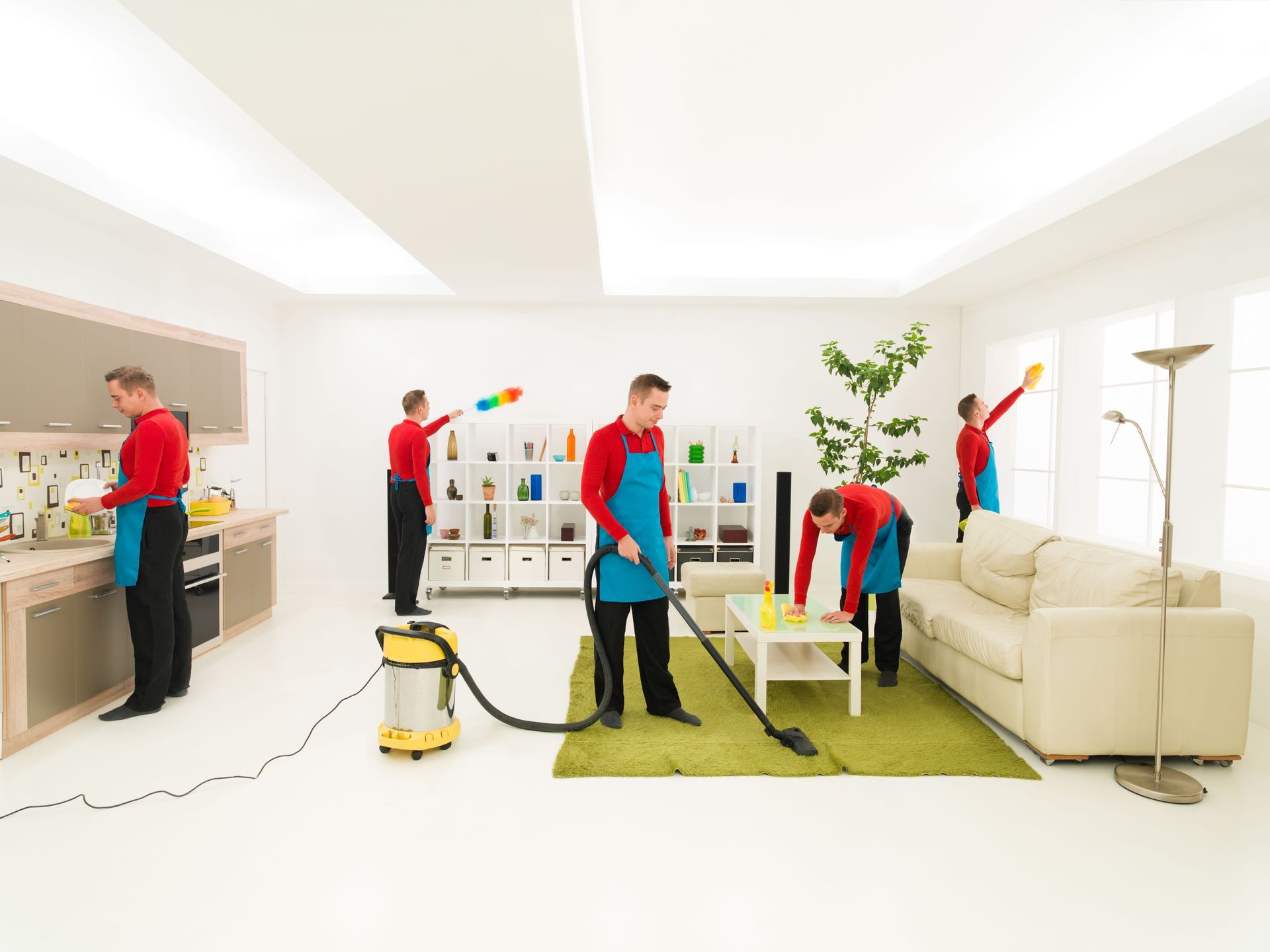 Multiple people cleaning a bright living room with a vacuum, mop, and supplies