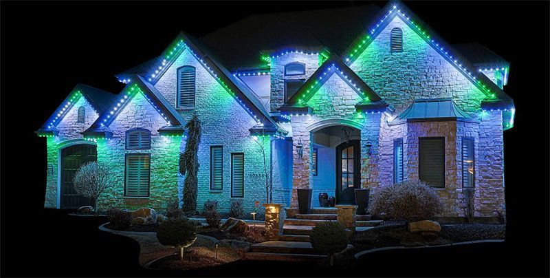 Brick house at night lit with blue, green, and white holiday lights