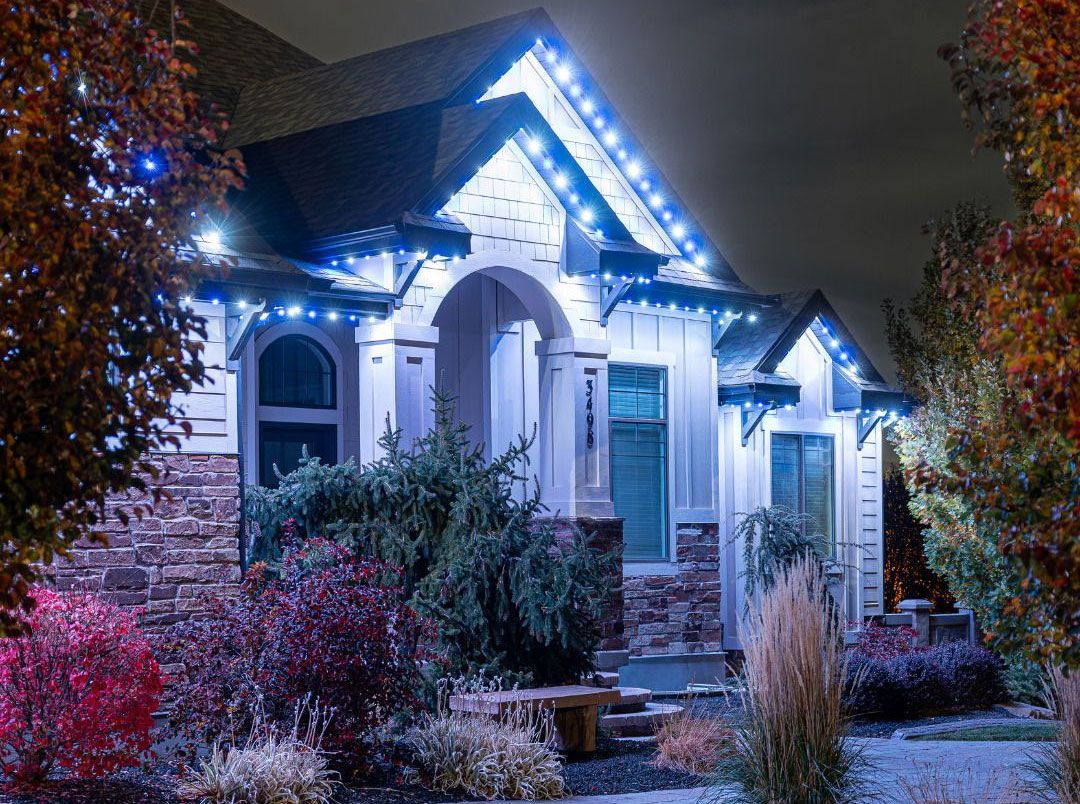 Snowy house lit with blue-white holiday lights at night