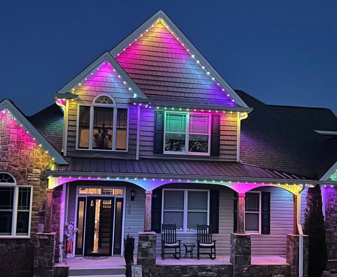 House at night with colorful purple, pink, and green holiday lights on the front porch and roofline