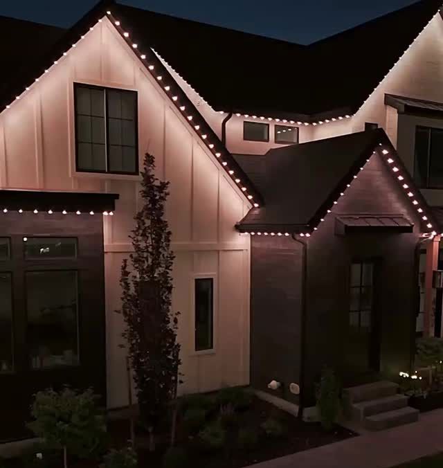 House at night outlined with white string lights along the roof and windows