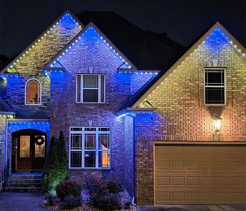 Brick suburban house lit with blue Christmas lights at night