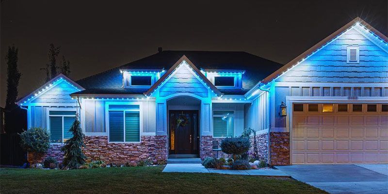 Blue-lit suburban house at night with a brick facade and two-car garage