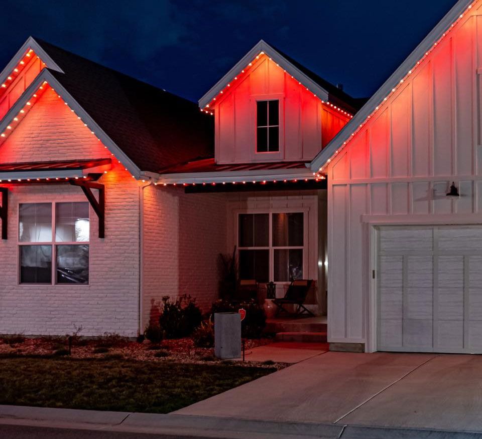 Suburban house at night with red Christmas lights glowing along the roofline