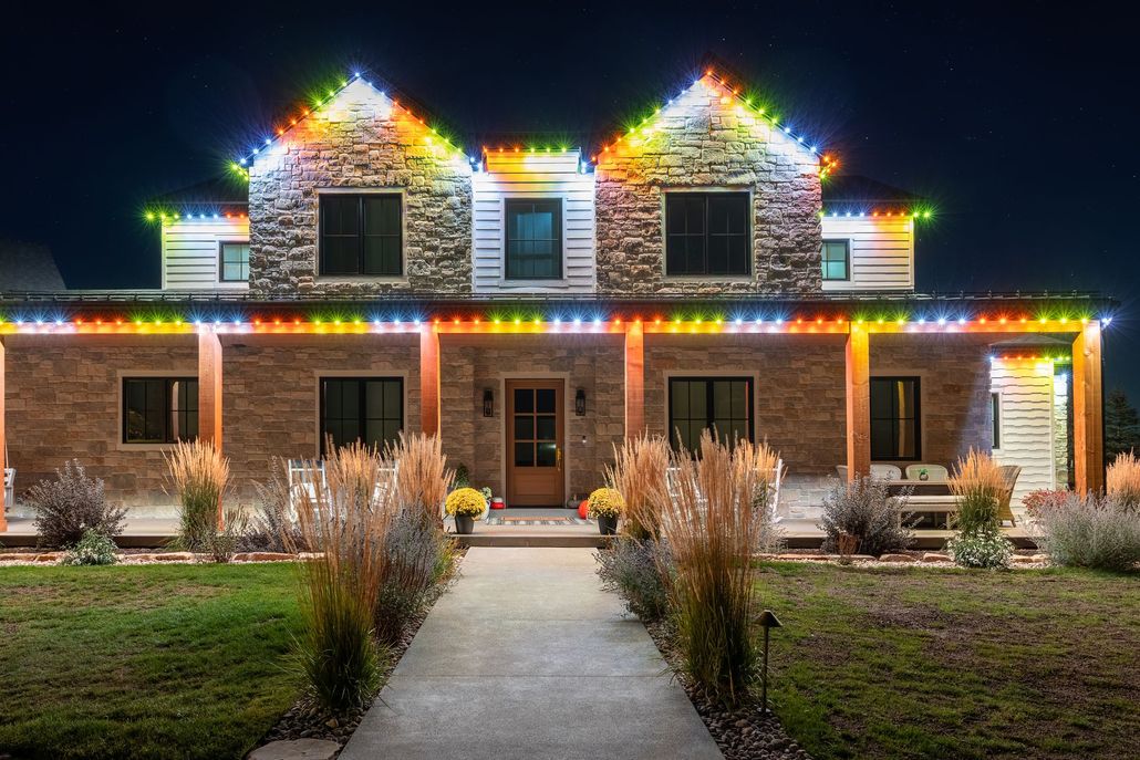 House decorated with multicolored Christmas lights at night, with a front walkway and lit windows.