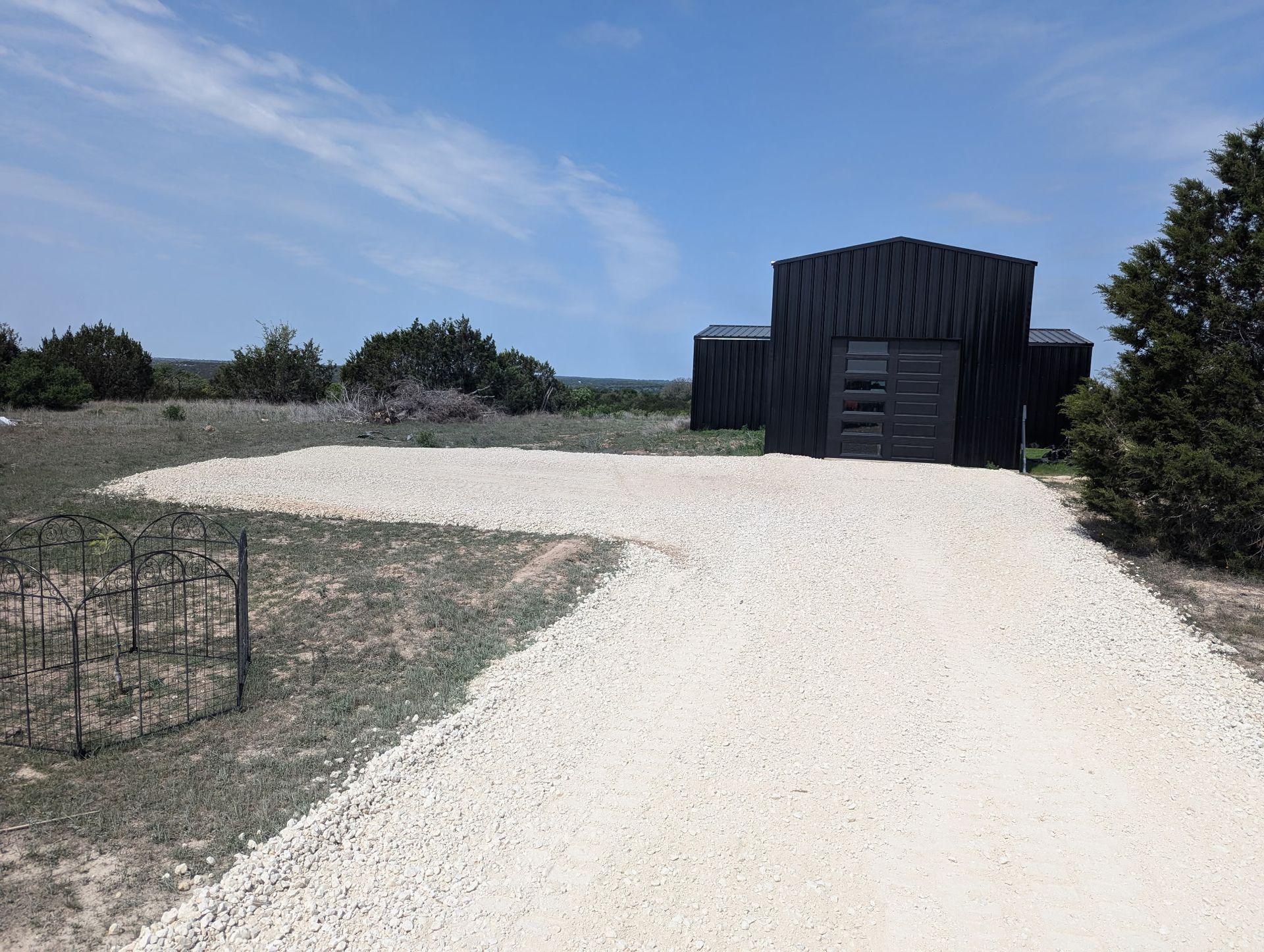 A gravel driveway leads to a black building
