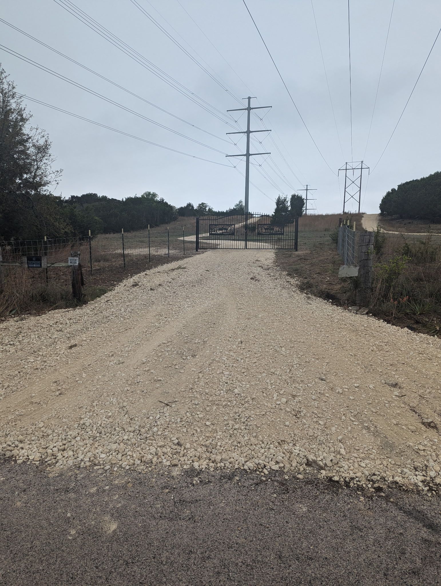 A gravel road with a lot of power lines on the side of it
