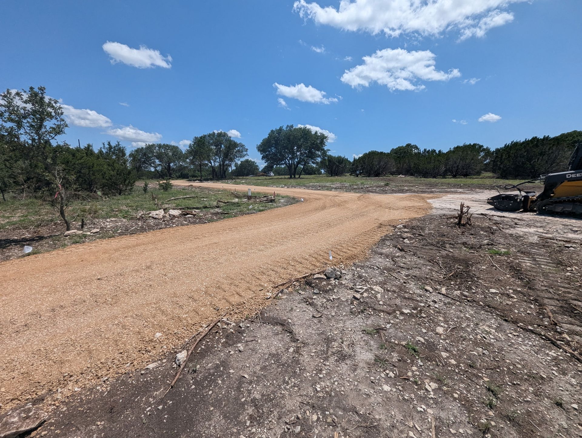 A dirt road going through a field with trees in the background
