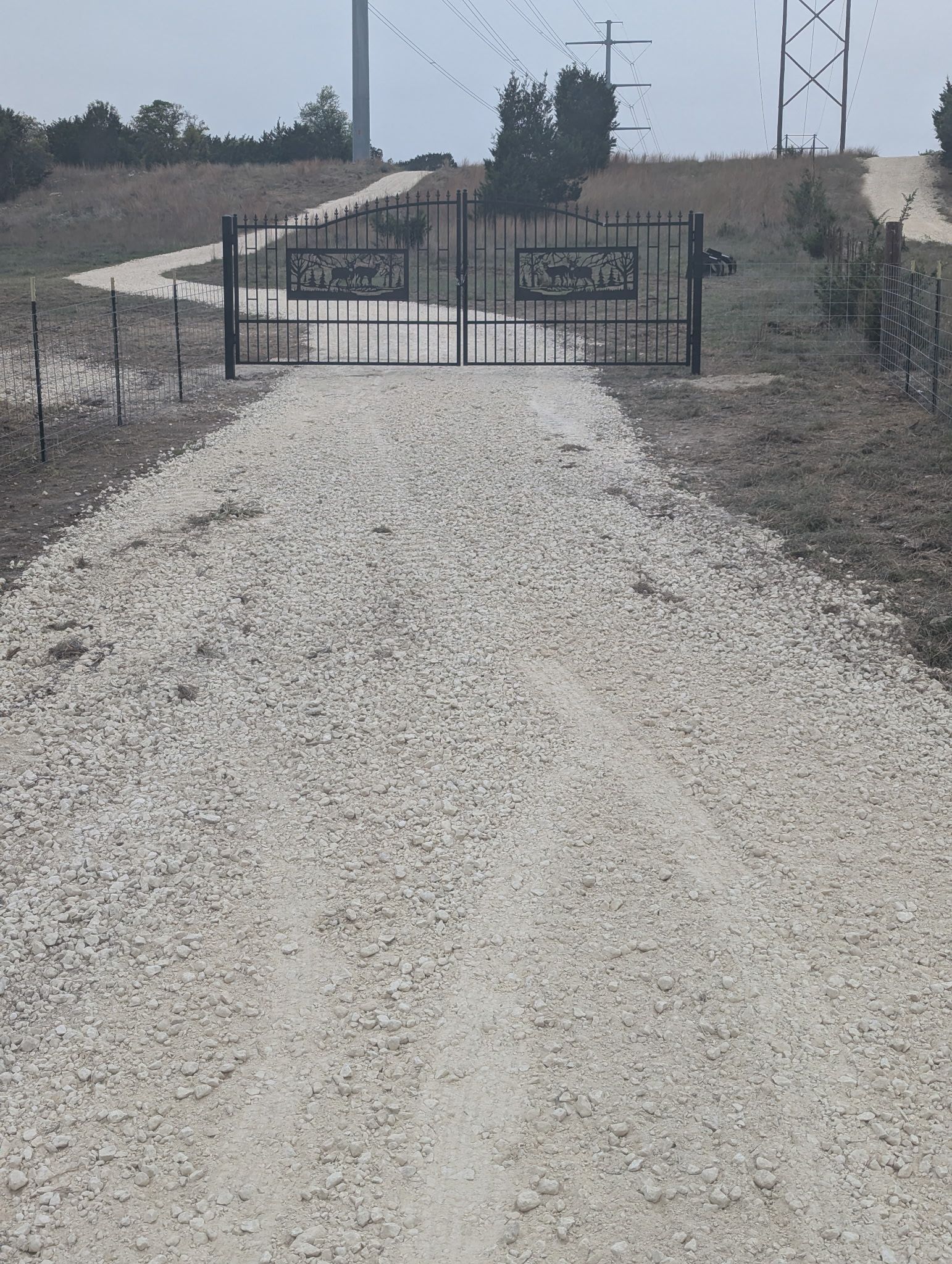A gravel road with a gate in the middle of it