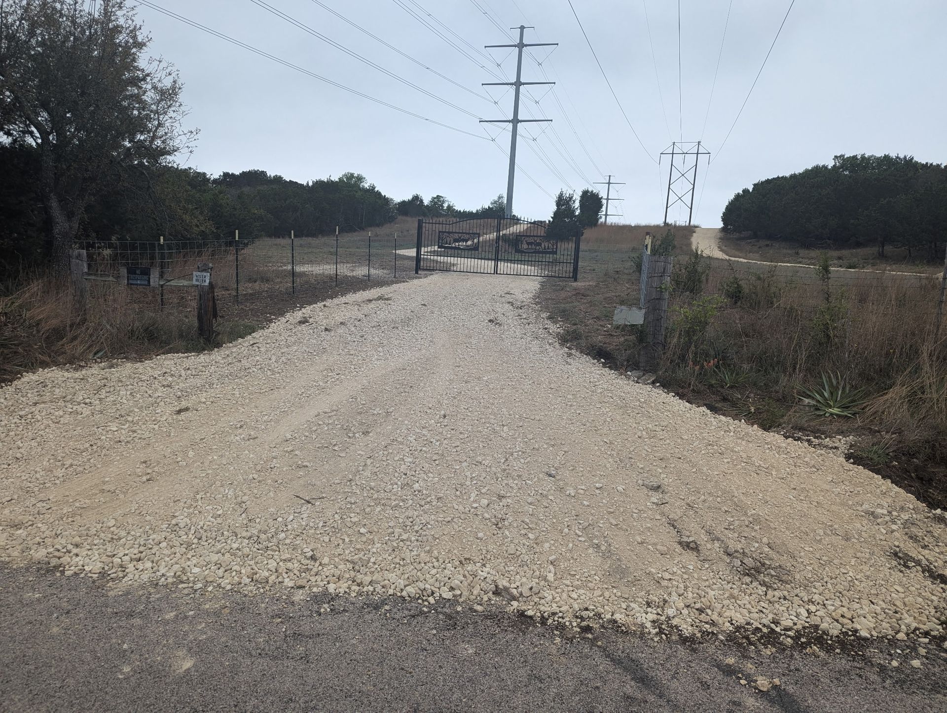 A gravel road with power lines on the side of it