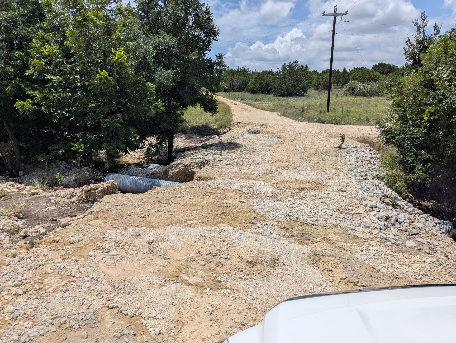 A white truck is driving down a dirt road