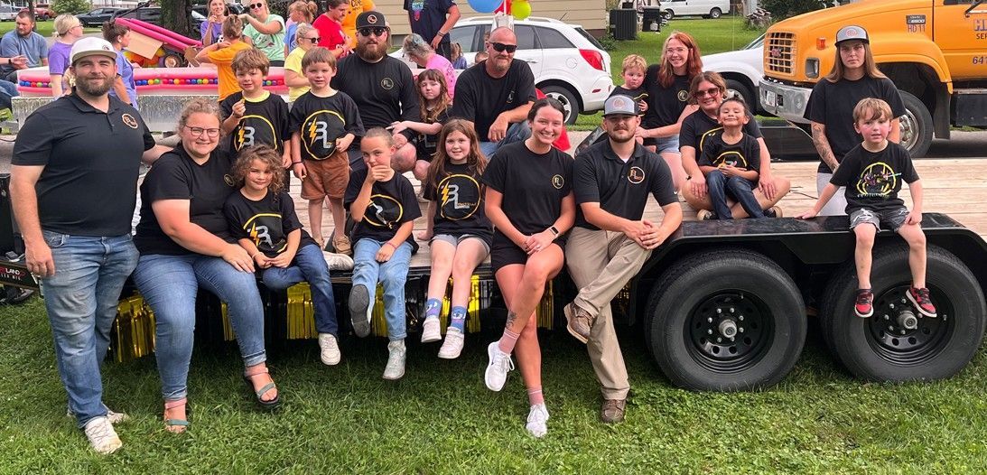 A group of people are posing for a picture in front of a trailer.