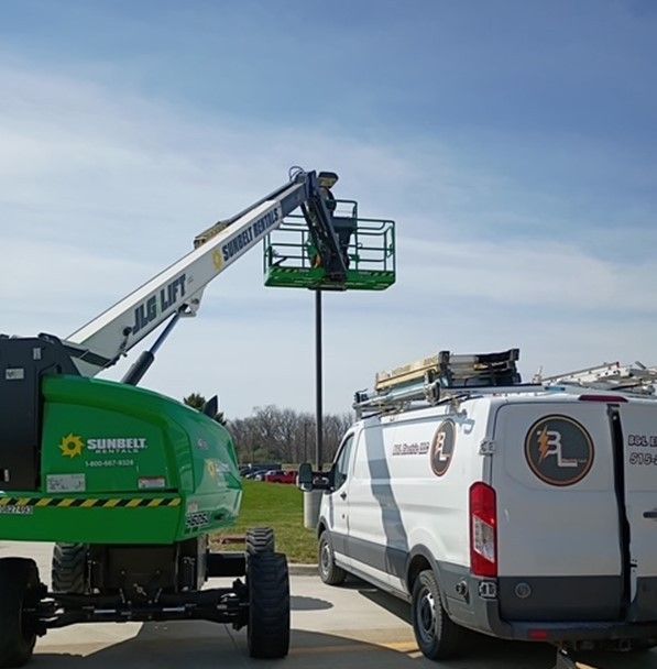 A white van is parked next to a green crane.