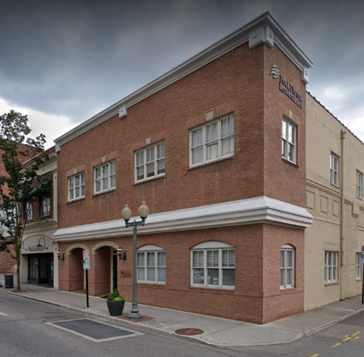 Brick corner building with white-trimmed windows and arched entrance on a quiet street corner