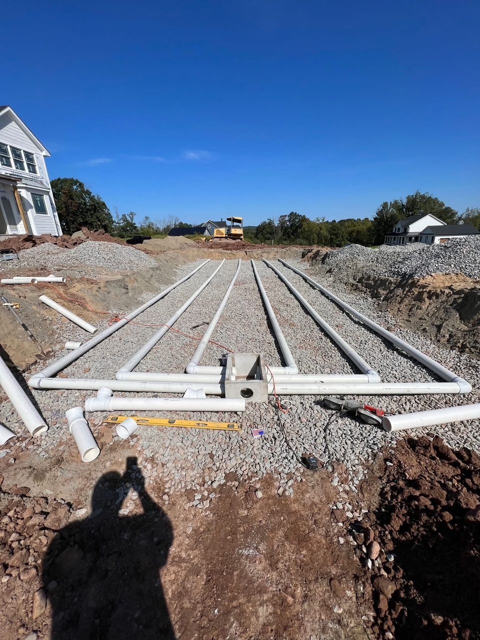 septic system installation with white pipes laid in gravel trenches