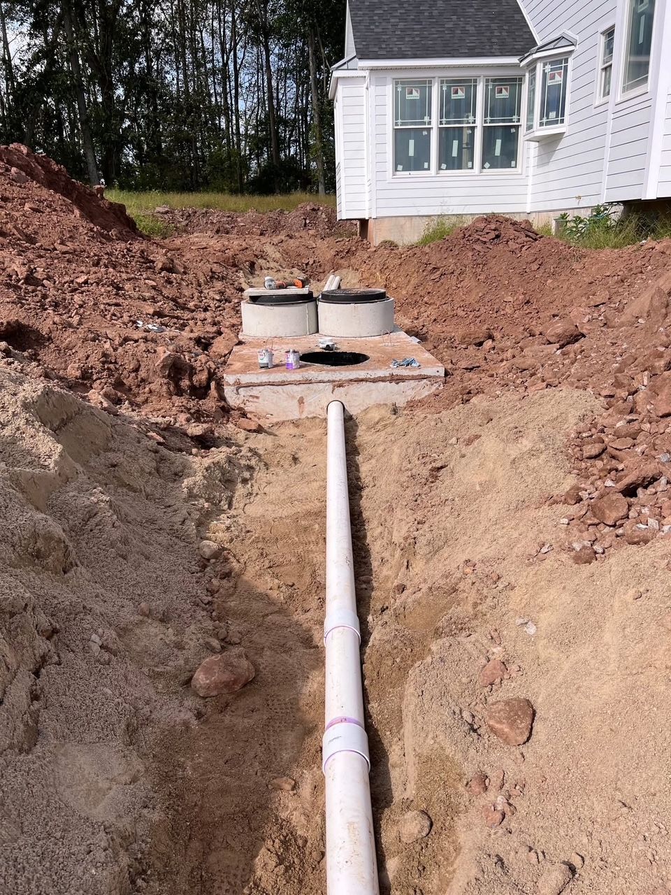 construction site with white pipe leading to concrete septic system tanks