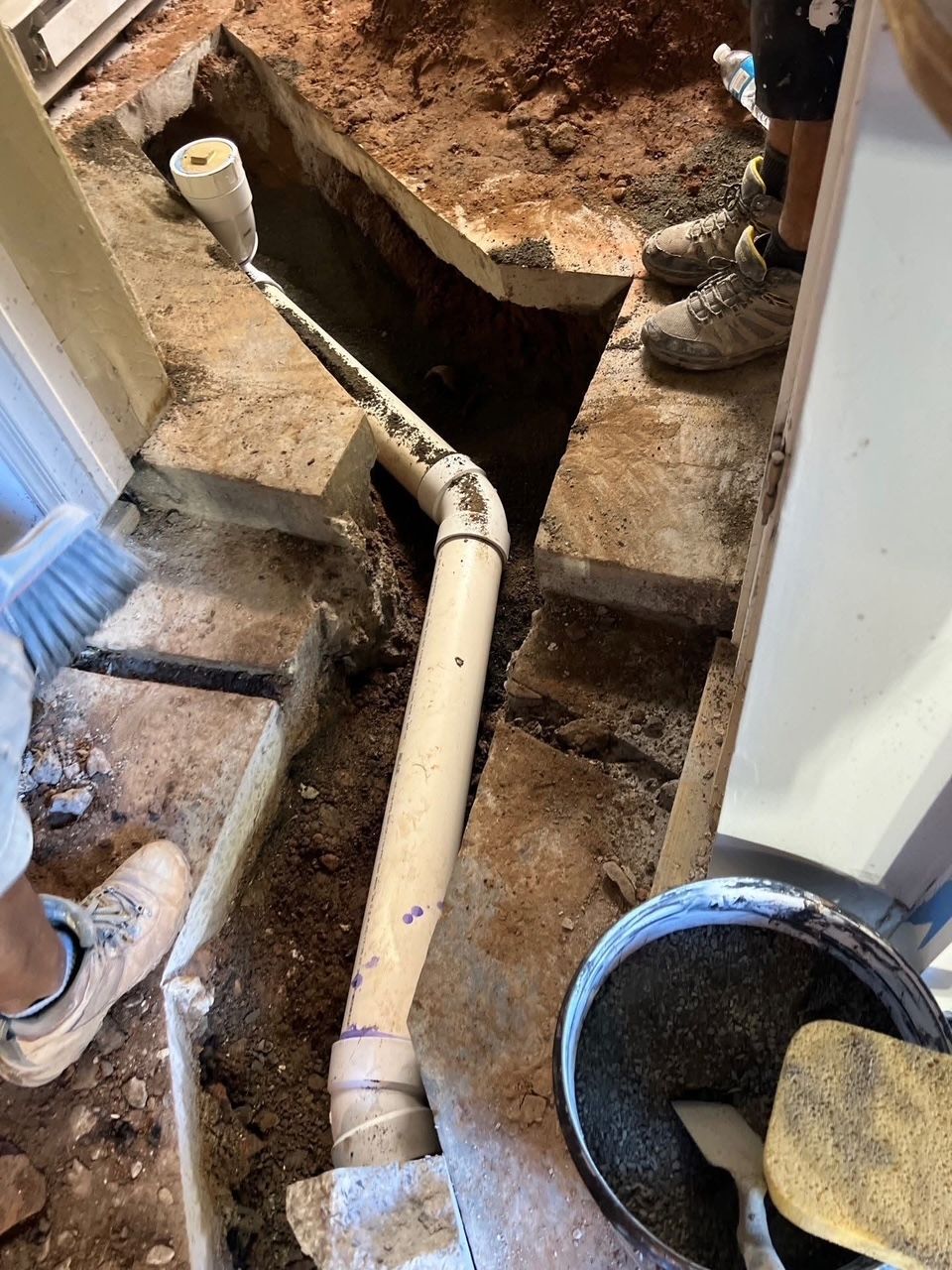 workers installing PVC drain pipe in a trench