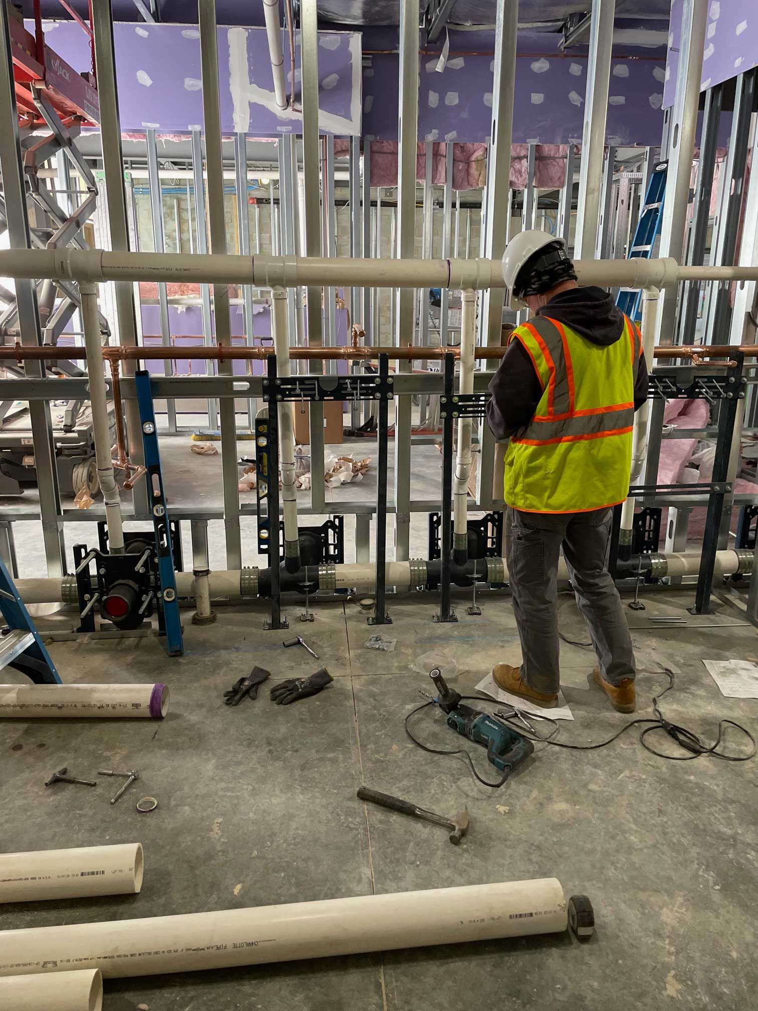construction worker in yellow vest and hard hat, piping in a building under construction